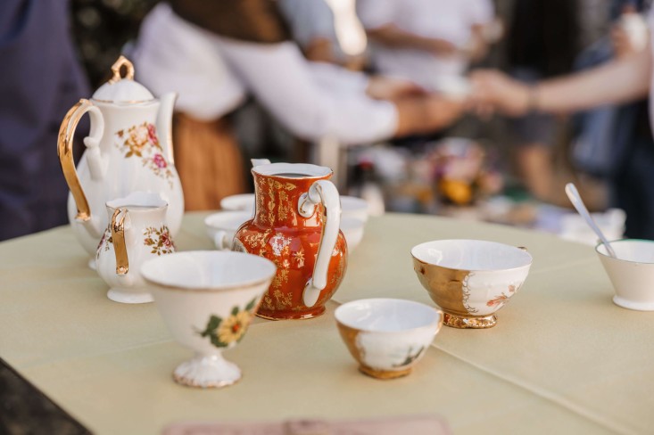 Starinski porcelanasti vrči, mlekarice in skodelice s cvetličnimi vzorci na mizi za strežbo kave na dogodku.